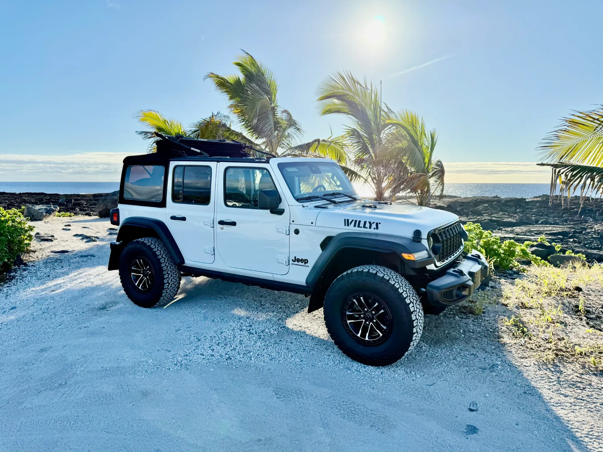 Gray Jeep Wrangler at Hawaii lava fields during sunset.